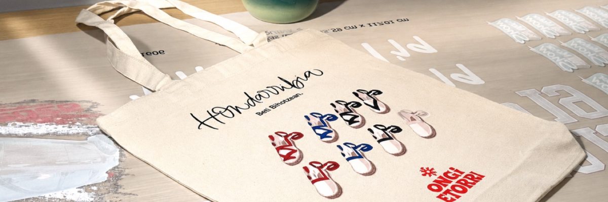Bolsa de algodón impresa con DTF sobre la mesa del taller, junto a los transfers recién impresos